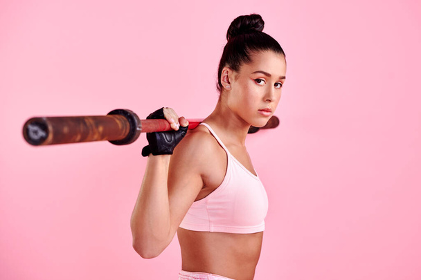 Vytrvalost přináší výsledky. Studio portrét sportovní mladá žena cvičení s činkou na růžovém pozadí - Fotografie, Obrázek