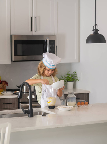 Kid chef cook wearing cooker uniform and chef hat preparing food on kitchen. Cooking, culinary and kids food concept - Foto, Imagen
