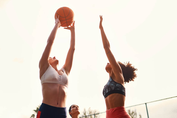 Welkom in de wereld van de competitieve sport. een diverse groep sportvrouwen die overdag samen een competitief basketbalspel spelen - Foto, afbeelding