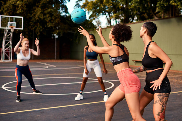 Eindelijk een pauze om de bal door te geven. een diverse groep sportvrouwen die overdag samen een competitief basketbalspel spelen - Foto, afbeelding