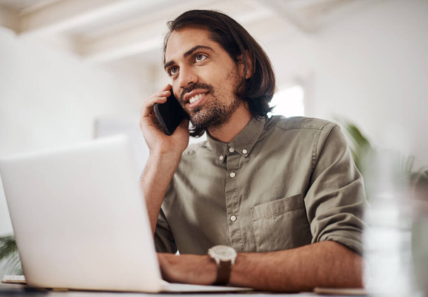 ¿Tienes alguna actualización para mí? un joven hombre de negocios hablando por celular mientras usa un portátil en una oficina - Foto, Imagen