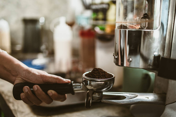 barista use bottomless filter with grinder machine at coffee shop. coffee maker concept. - Foto, Imagem