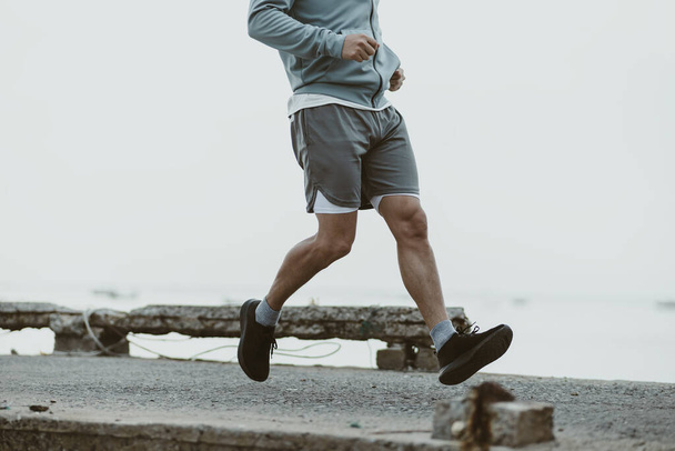 healthy lifestyle young fitness man running at seaside old bridge. Outdoor workout,  Healthy lifestyle concept. - Foto, imagen