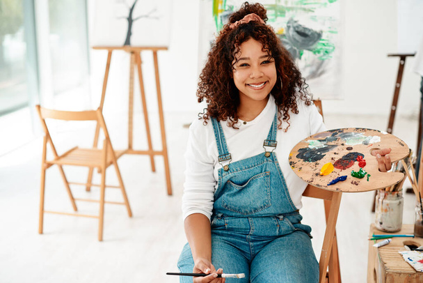 Painting brings out my inner child. Cropped portrait of an attractive young artist sitting alone in the studio and holding a palette during an art class - Photo, Image