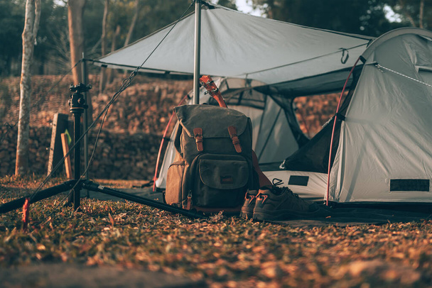 Camping equipment, bags, shoes, ukulele, tripod beside the tent in the morning. Object camp, Travel and vocation concept. - Photo, image