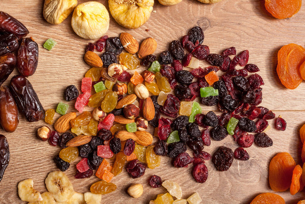 Gedroogde vruchten en noten op houten achtergrond. Gezonde voeding. Verse rauwe noten en fruit - Foto, afbeelding