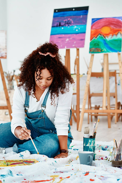 Zagubiony w artystycznym świecie. atrakcyjny młody artysta siedzący samotnie i malujący podczas zajęć plastycznych w studio - Zdjęcie, obraz