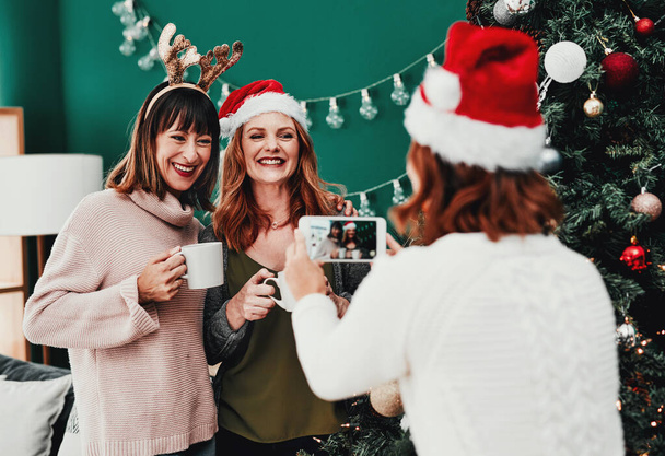 Залишайтеся так. весела жінка середнього віку фотографує своїх двох друзів вдома під час Різдва
 - Фото, зображення