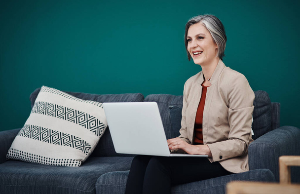 Kocham to, czym się zajmuję. atrakcyjna dojrzała bizneswoman siedzi sama i korzysta z laptopa w swoim biurze - Zdjęcie, obraz