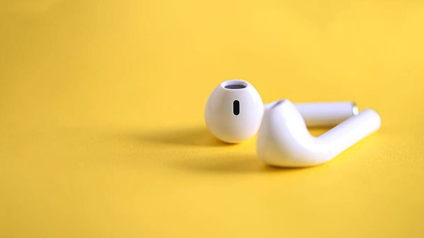 Λευκά ακουστικά ασύρματα ακουστικά σε κίτρινο φόντο - Φωτογραφία, εικόνα
