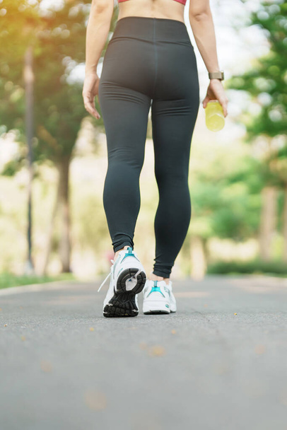 女性のジョギングや午前中に道路を歩くと、スポーツシューズでは、公園の外で実行されている若い大人の女性は、アスリートの足の筋肉。運動、健康、健康的なライフスタイルとワークアウトの概念 - 写真・画像