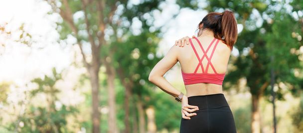 Mladá fitness žena drží své sportovní zranění rameno a krk, svaly bolí během tréninku. Asijský běžec fena mít tělesný problém po cvičení venku v létě - Fotografie, Obrázek