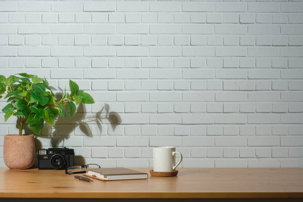 Ξύλινο γραφείο στο σπίτι με σημειωματάριο, φωτογραφική μηχανή και γλάστρα, αντίγραφο χώρο για το σχεδιασμό για την παρουσίαση του προϊόντος φόντο. - Φωτογραφία, εικόνα