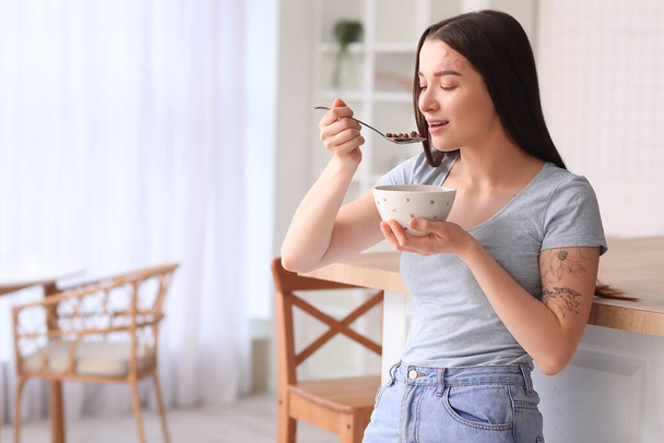 Nuori nainen syö maissi pallot lusikka keittiössä - Valokuva, kuva