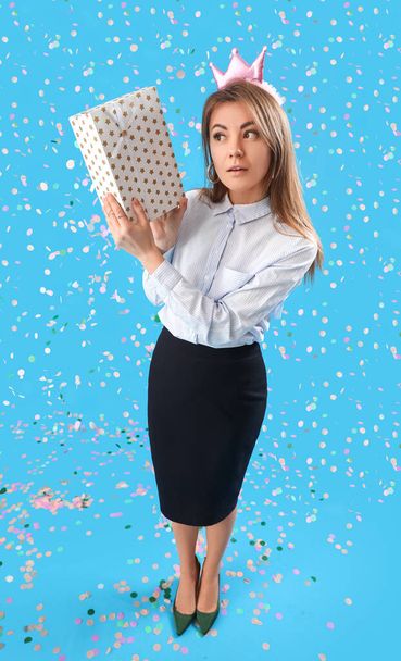 Beautiful businesswoman with gift celebrating Birthday on blue background - Photo, Image