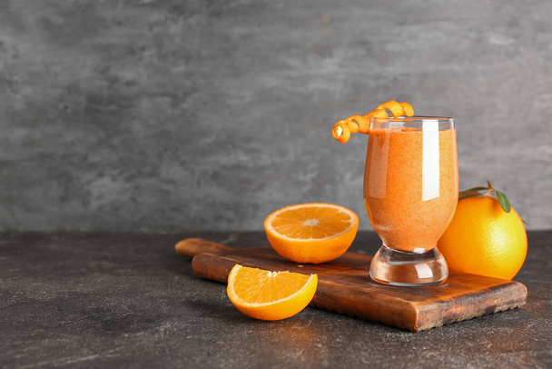 Bord met glas gezonde oranje smoothie op zwarte grunge tafel - Foto, afbeelding