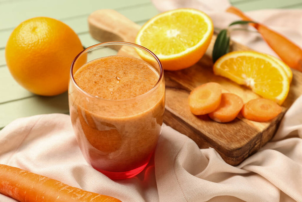 Copo de smoothie laranja saudável e ingredientes em mesa de madeira verde - Foto, Imagem