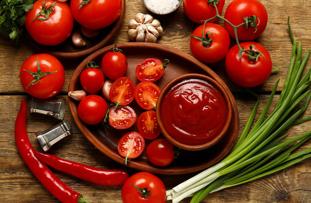 Bowl with tasty ketchup and fresh vegetables on wooden background - Foto, Imagen