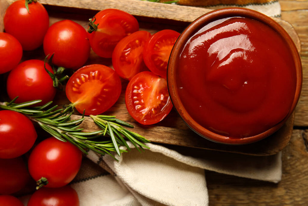 Bowl with tasty ketchup and fresh vegetables on table, closeup - 写真・画像
