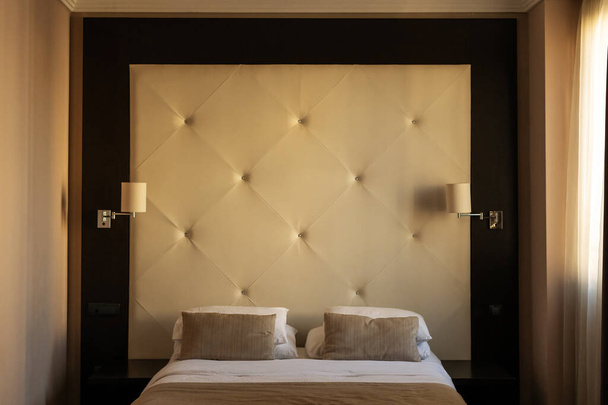 Hotel room bedroom furniture - a bed with headboard, pillows and bedside lamps - Φωτογραφία, εικόνα