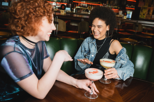 щасливі багатоетнічні друзі сміються і розмовляють біля піни коктейлів в барі
  - Фото, зображення