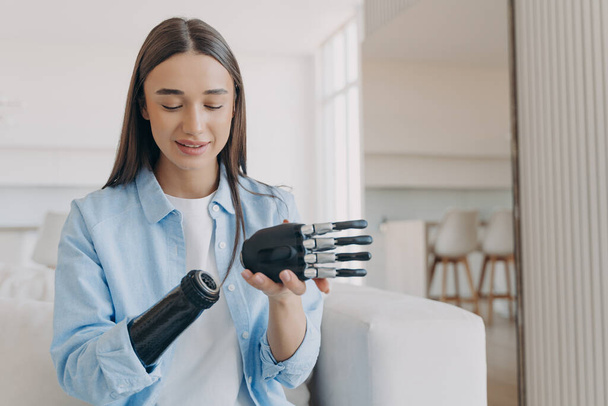 Disabled young woman is assembling bionic arm with hand. Prosthesis is connecting in wrist joint. Cyber sensor hand has processor chip and buttons. European girl has high tech carbon electronic hand. - Foto, Imagem