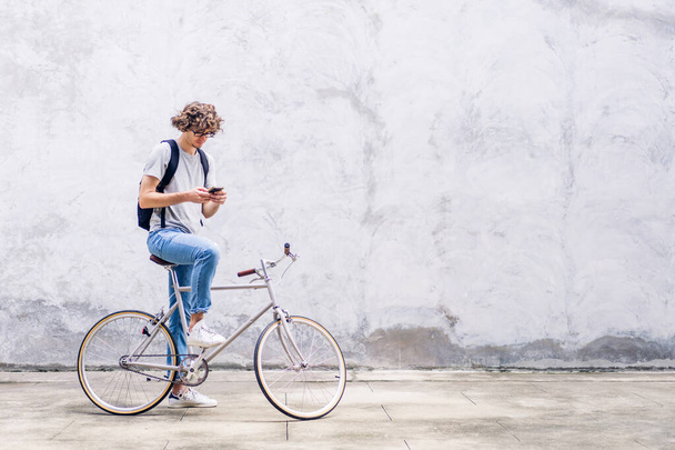 Portrait of casual hipster handsome businessman with backpack looking on smartphone while commuting riding bicycle on the street city way go to work.business travel transport bike concept - Fotó, kép