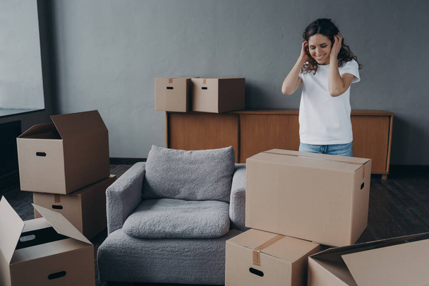 Happy young spanish woman relocates alone. Single lady moves and packing things. Girl packing cardboard boxes. European woman unpacking boxes in new house. Real estate purchase and mortgage concept. - Valokuva, kuva