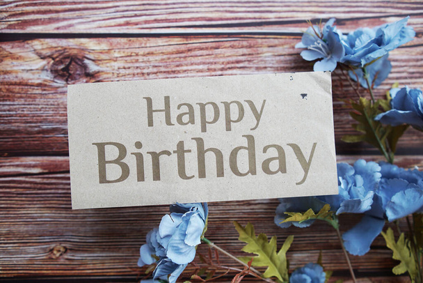 Happy Birthday text message with flower decoration on wooden background - Photo, Image