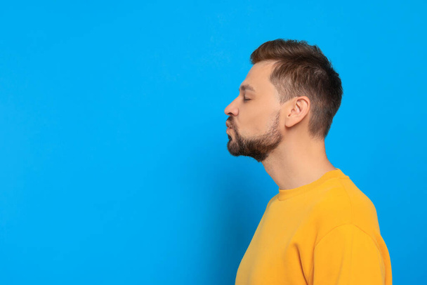 Handsome man blowing kiss on light blue background. Space for text - Photo, Image