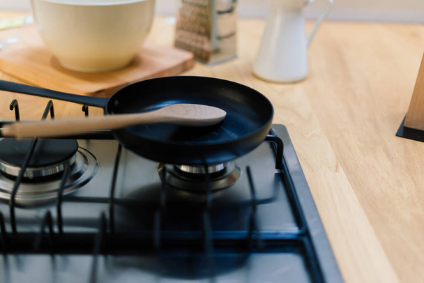 Spatola in padella teflon rivestimento padella sul fornello a gas contro cucchiaio appeso in piccola cucina - Foto, immagini