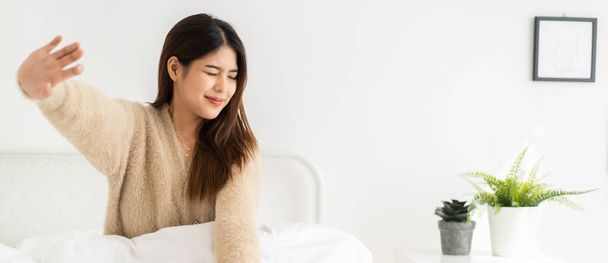 Portrét usmívající se veselá krásná hezká asijská žena čisté čerstvé zdravé bílé kůže představovat úsměv v pyžamu bílé oblečení.Dívka kácení relaxovat a užívat si čas na posteli doma. - Fotografie, Obrázek