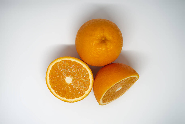 Цілі і розрізані в 2 половини апельсини на білому фоні студії вид зверху
 - Фото, зображення
