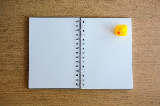 Cuaderno y pato amarillo en panel de madera
 - Foto, Imagen