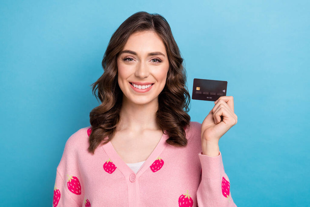 Photo of sweet charming lady dressed pink cardigan rising credit card isolated blue color background. - Foto, immagini
