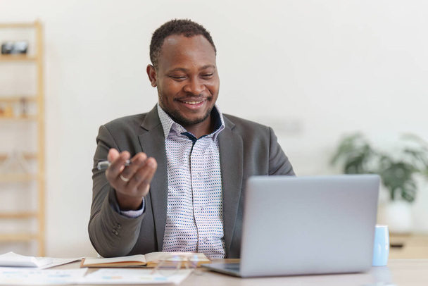 Lächelnde American African Banker oder Buchhalter Videoanruf mit Kunden und macht Finanzbericht und Studien Jahreszahlen, analysiert Gewinne. - Foto, Bild