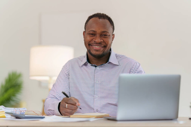 Sorrindo Africano americano faz relatório financeiro e estuda números anuais, analisa lucros. Contabilista verifica o estado das finanças. - Foto, Imagem