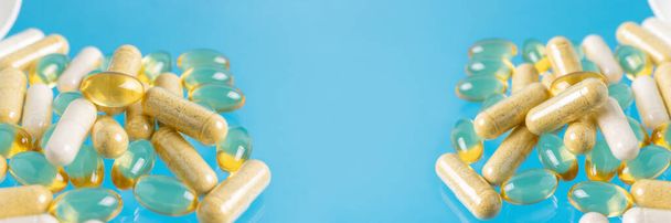 Различные многоцветные капсулы, травяные витамины или лекарства для лечения на голубом фоне, медицина и здравоохранение концепции, крупным планом. - Фото, изображение