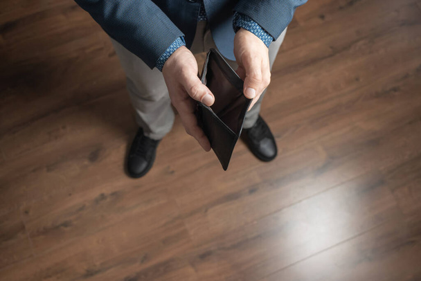 Well dressed man holding empty leather wallet. Financial crisis and bankruptcy concept. - Photo, Image