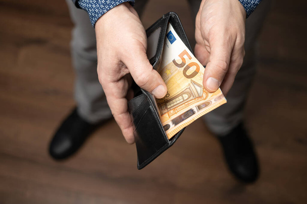 Dobře oblečený muž si dává do kožené peněženky, eurobankovek, papírové měny Evropské unie hromadu peněz. - Fotografie, Obrázek