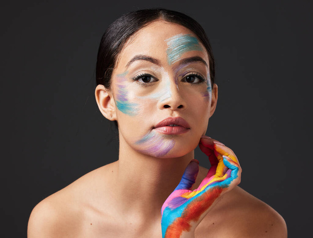 Woman, face and beauty portrait with color paint art on hand in studio. Creative skin and makeup on female aesthetic model on gray background for lgbtq rainbow inspiration hands or facial cosmetics. - Фото, зображення