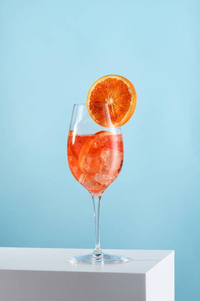 Glass of Aperol spritz cocktail on light blue background - Фото, зображення