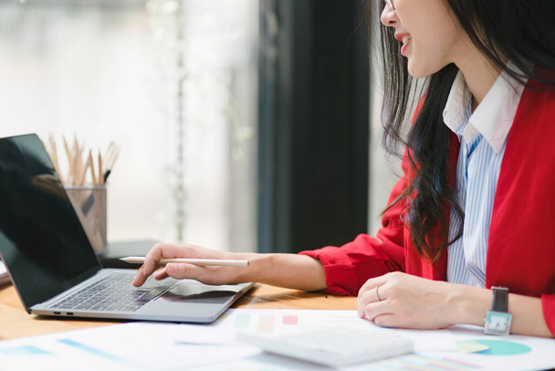 Обрезанный снимок красивой азиатской бизнесвумен использует цифровой ноутбук за ее столом в современном офисе - Фото, изображение