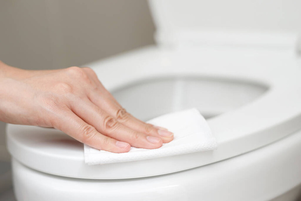 kobieta za pomocą bibuły oczyścić toaletę w łazience w domu. - Zdjęcie, obraz