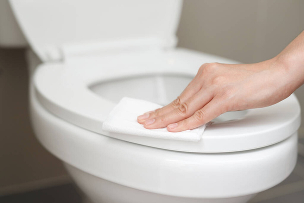 γυναίκα που χρησιμοποιεί χαρτί υγείας καθαρίζει την τουαλέτα στο μπάνιο στο σπίτι. - Φωτογραφία, εικόνα