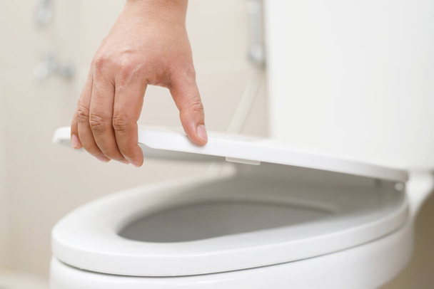 lähikuva naisen kädestä, joka sulkee WC-istuimen kannen. Hygienia- ja terveydenhuollon käsite. - Valokuva, kuva