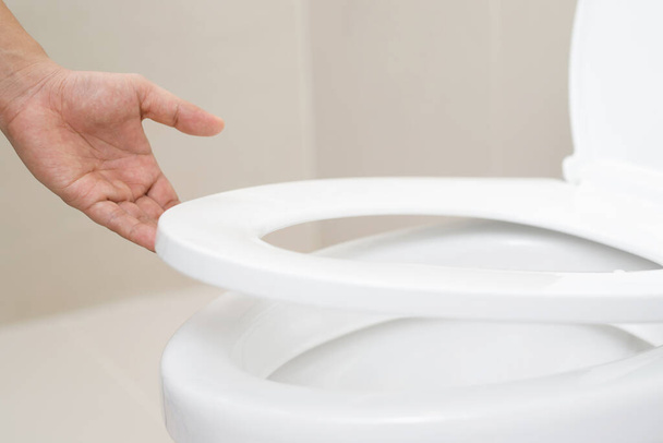 main fermée d'une femme fermant le couvercle d'un siège de toilette. Concept d'hygiène et de soins de santé. - Photo, image