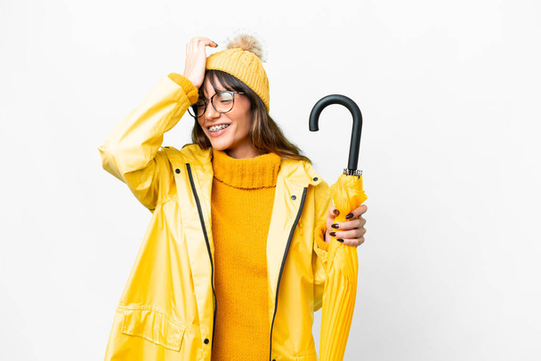 Young caucasian woman with rainproof coat and umbrella over isolated white background has realized something and intending the solution - Photo, image