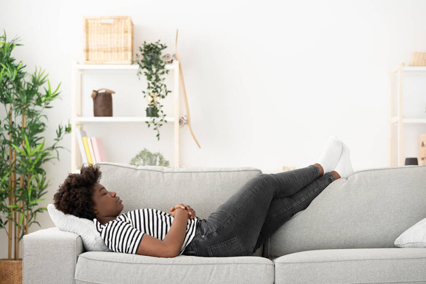 アフリカ系アメリカ人の若い女性が眠っているか、コピースペースでソファにリラックス - 写真・画像