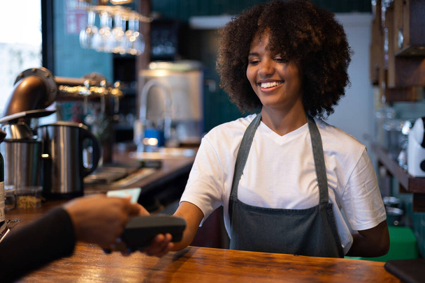 Young African waitress getting paid - Foto, Imagen